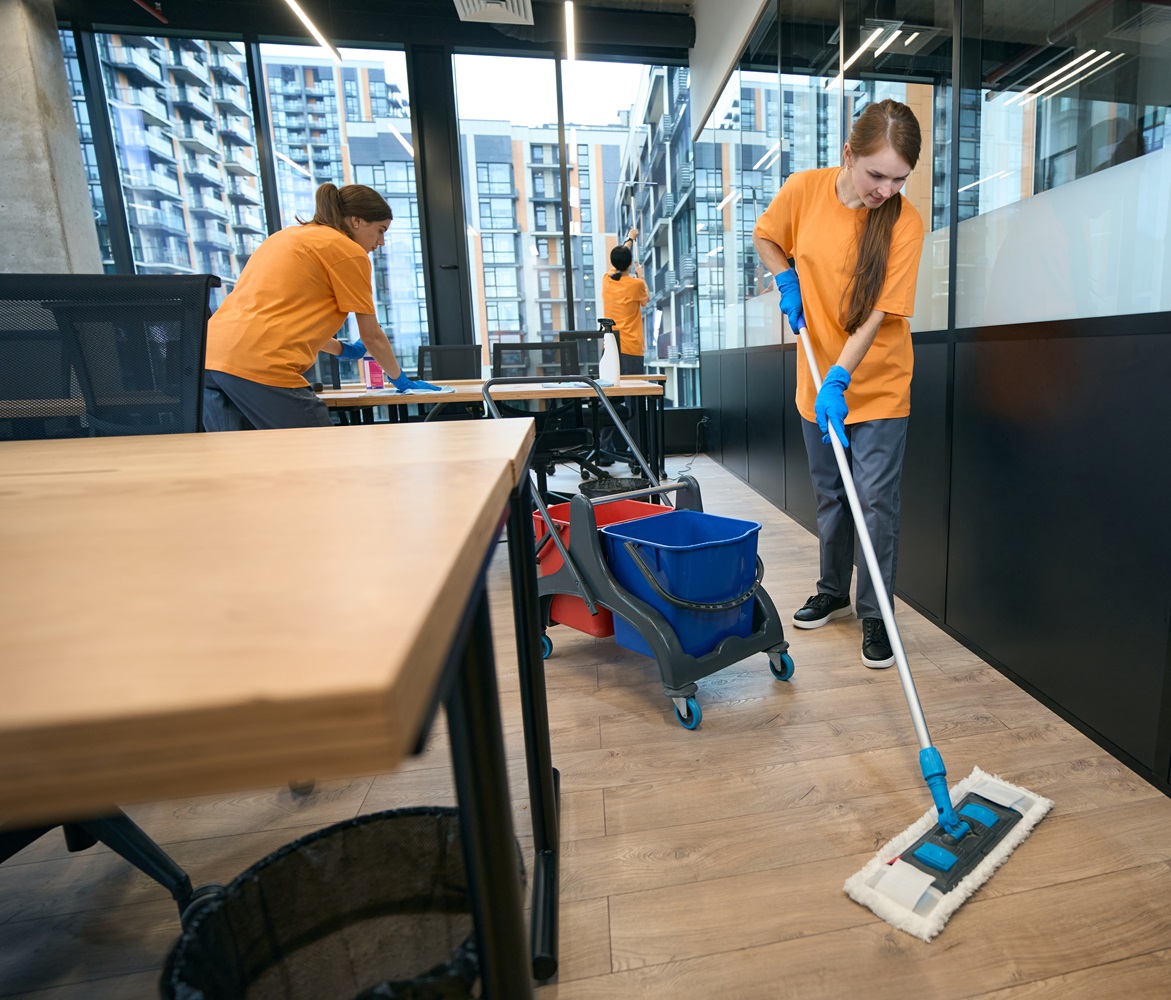 Team of cleaners work in coworking area, women clean all surfaces
