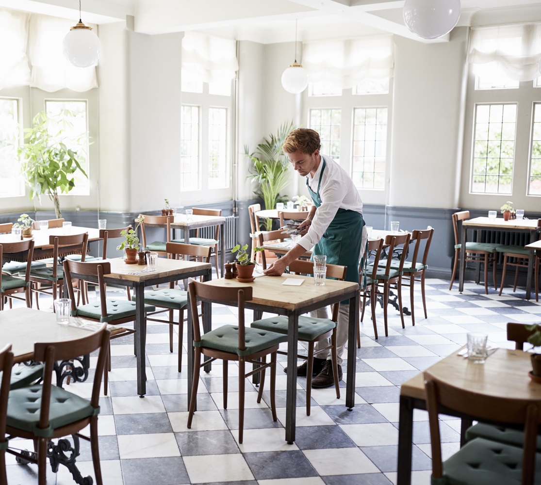 Waiter Laying Tables In Empty Restaurant